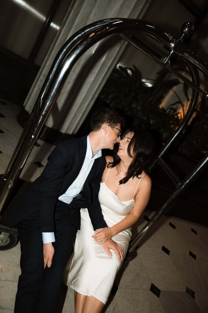 Romantic couple sit on a luggage cart at Emery Hotel in Minneapolis, Minnesota.