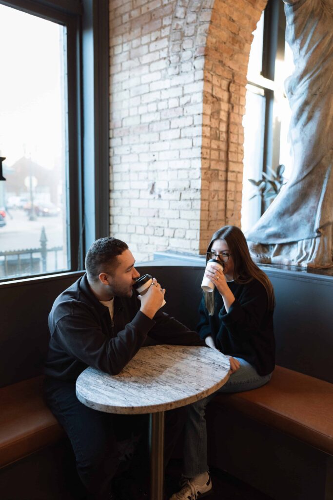 Couple sit and drink their coffee during an engagement session in Minnesota.