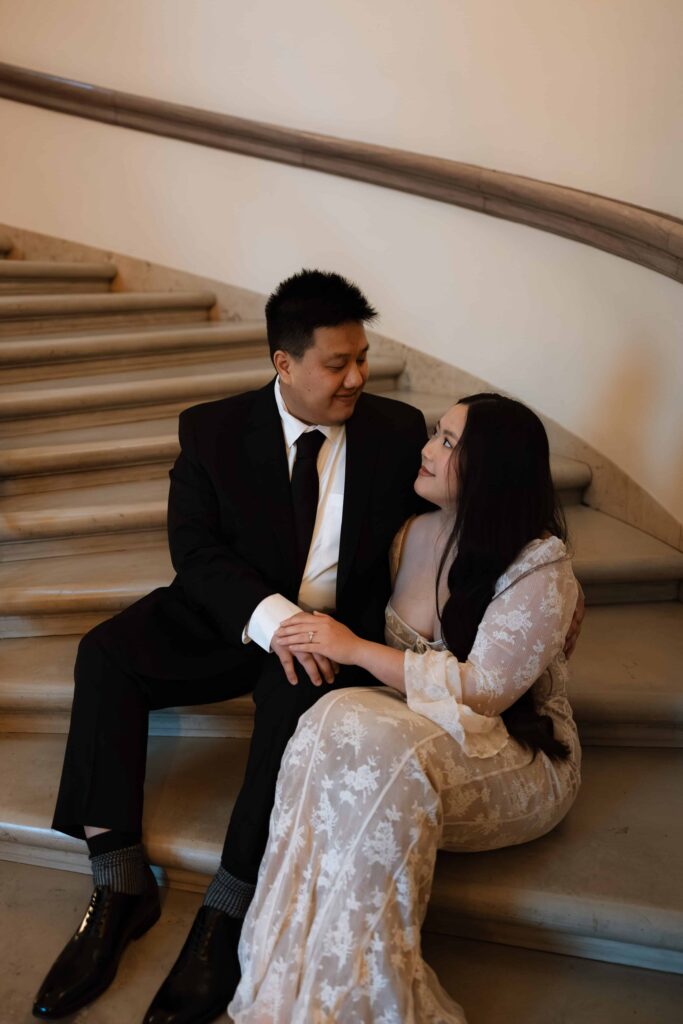 Engaged couple sit on a staircase at one of the best engagement session locations in the twin cities.