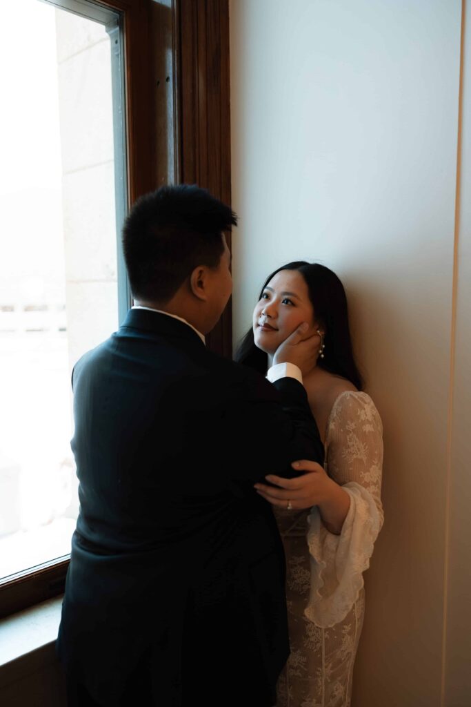 Man holds his fiance's face in his hands and look at her lovingly.