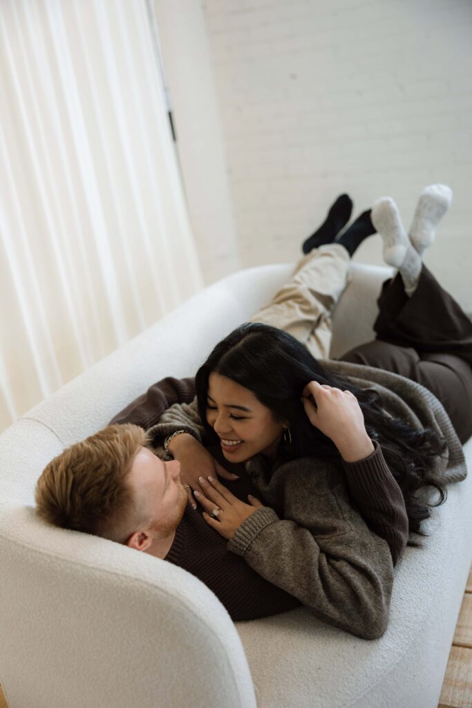 Engaged couple laying on a couch at a studio in St. Paul, Minnesota.