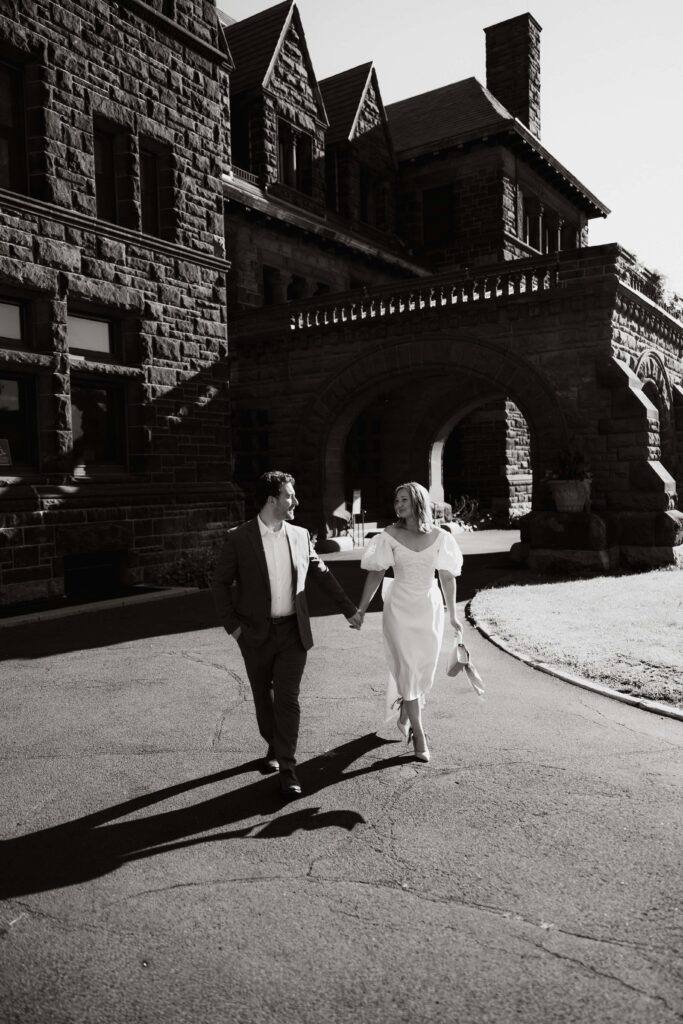 Couple walk while holding hands in front of the historic James J. Hill house in St. Paul, Minnesota.