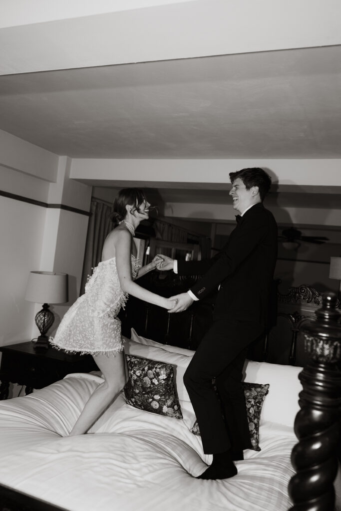 The bride and groom jump on the bed in one of the elegant bedrooms at The Little Daisy. They changed into their second outfits to continue to celebrate their wedding day.