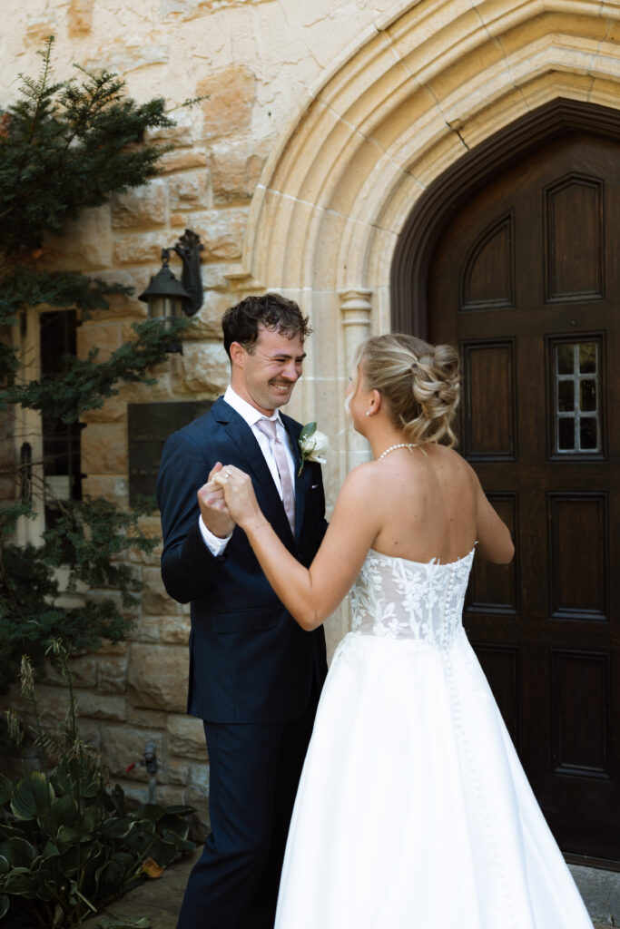Groom looks lovingly at his bride during their first look at Plummer House in Rochester, Minnesota.